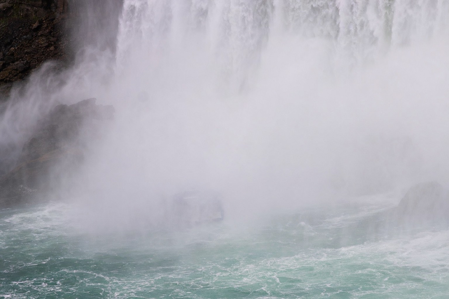 A tour boat almost invisible inside the spray at the foot of Horseshoe Falls