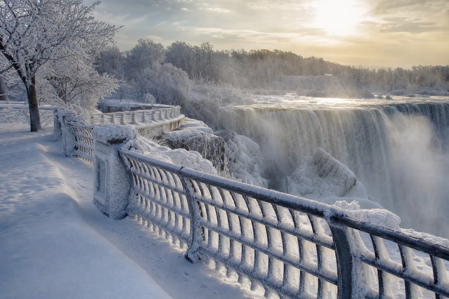 The gorge rim in deep winter, railings and trees cased in frozen mist, the falls running behind ice formations