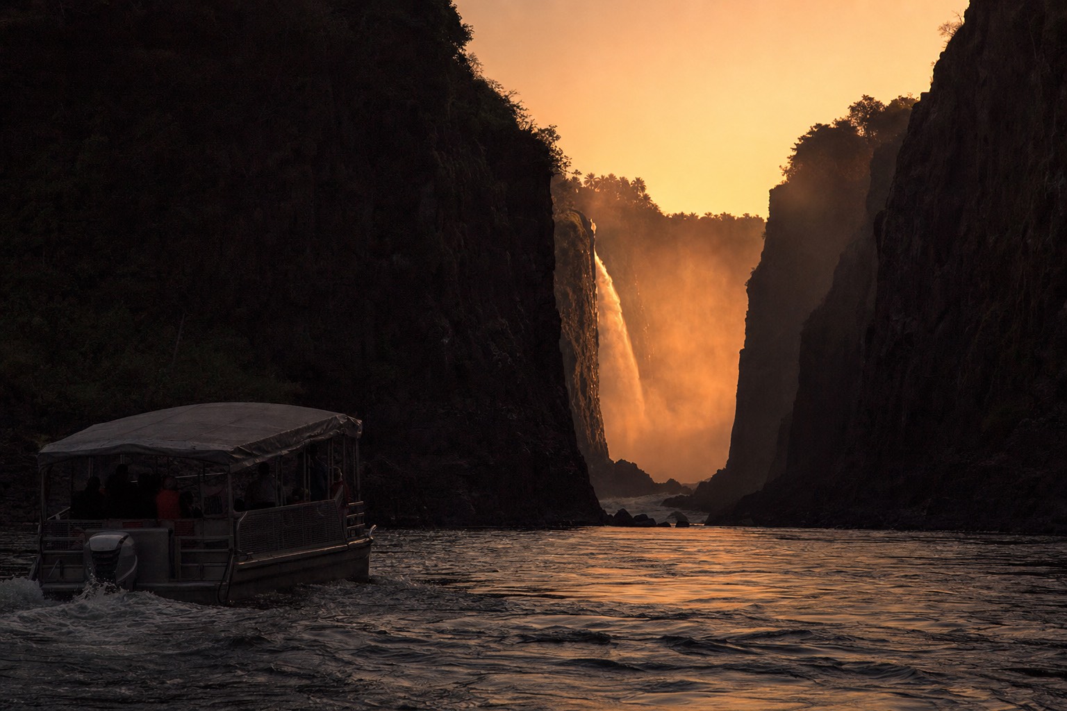 The boat returning to its landing at dusk, the gorge in shadow and the last light on the spray column