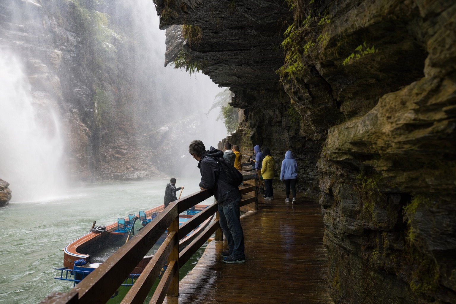 Visitors on the wooden boardwalk at gorge level beside the boat landing, spray drifting over the railings