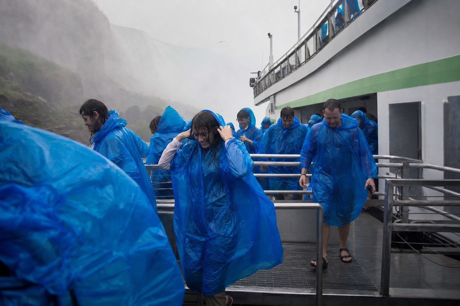 Passengers in wet ponchos coming off the boat at the landing, laughing and wringing out sleeves